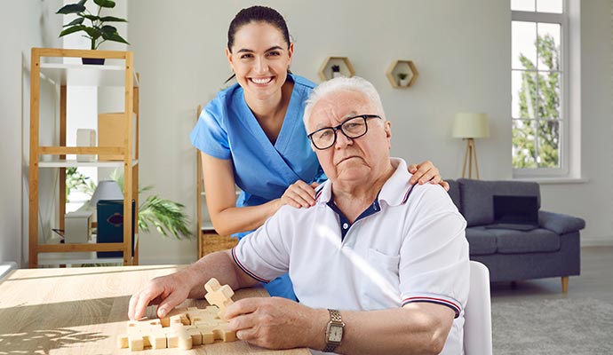 care giver standing next to an old man sitting on a chair