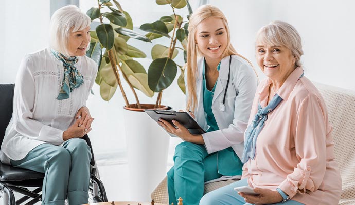 nurse and old woman sitting on a sofa