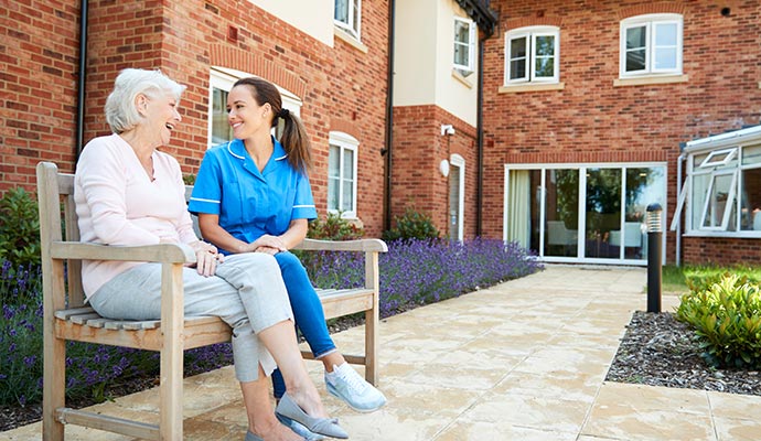 old woman and a nurse sitting in a bench