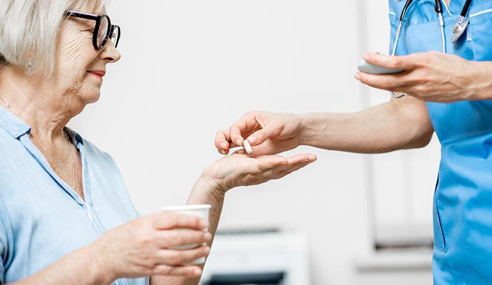 nurse giving pills to senior woman